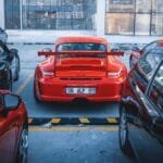 Red sports car parked among others in an Ankara parking lot on a cool day.